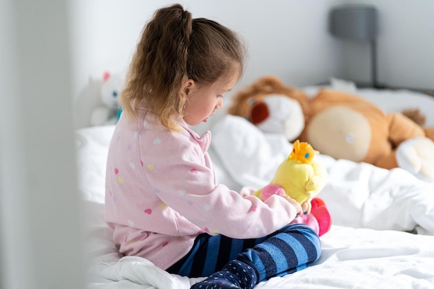 Pleasant and cozy Happy child feel cozy in bedroom Small girl in cozy wear Home clothing for comfort Leisure or slumber wear Bedtime Nursery room Feeling relaxed and comfortable Stay cozy