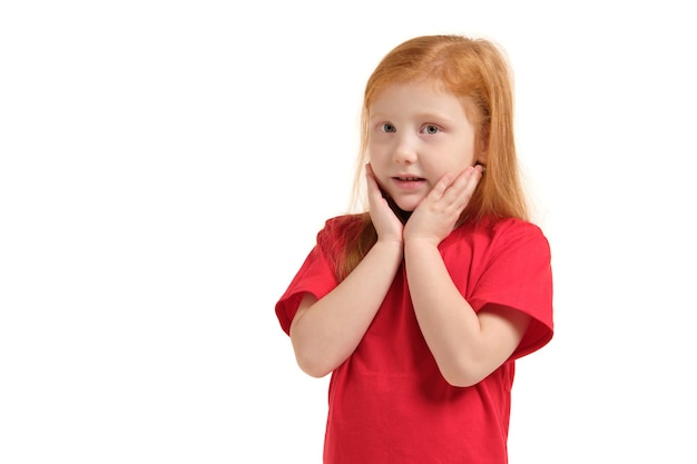 Pleasant cute upbeat little girl holding her hands near face and smiling while expressing joy.