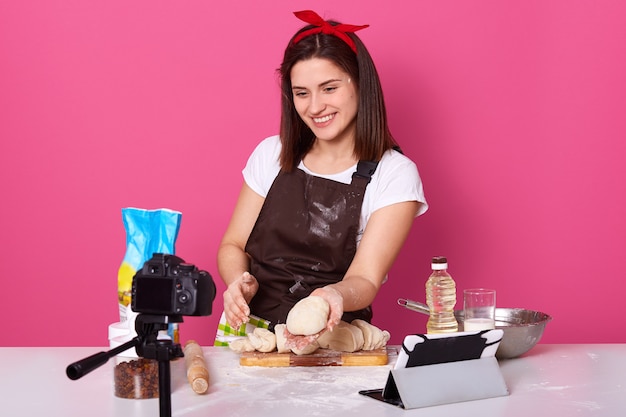 Pleasant energetic young lady holding dough in one hand