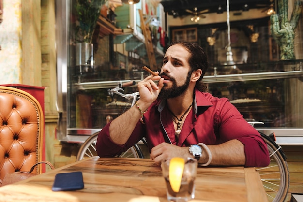 Pleasant handsome man holding a cigar while smoking it