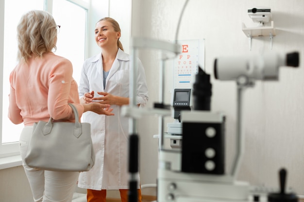 Pleasant kind doctor in long white robe talking to patient