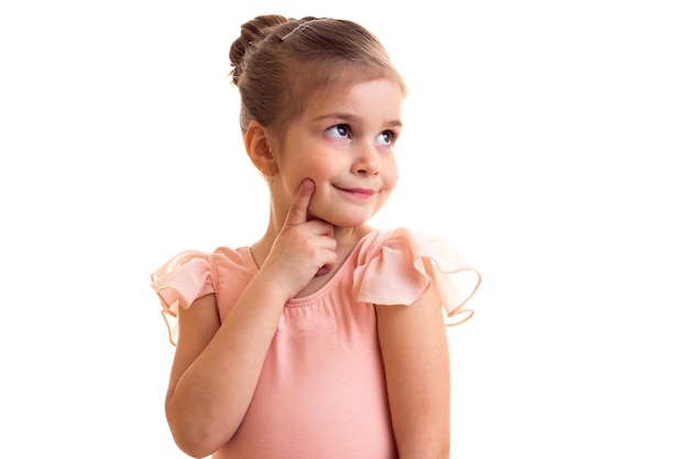 Pleasant little girl in pink dress with bundle dancing on white background in studio