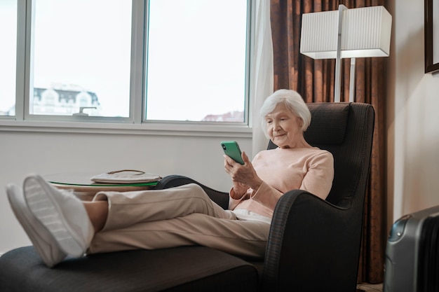 Pleasant-looking senior lady texting and looking involved