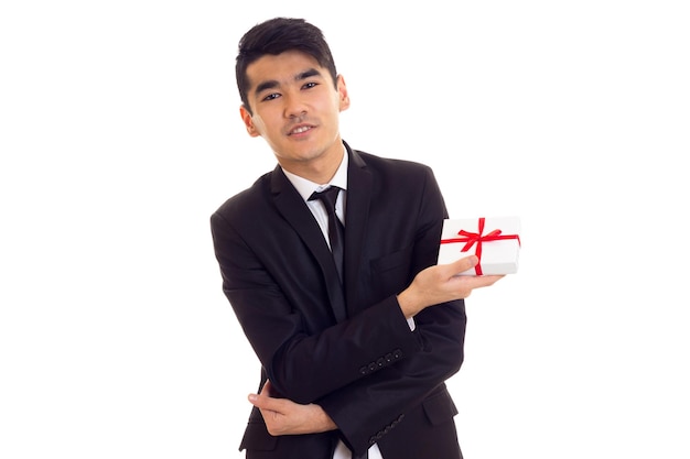 Pleasant man with black hair in white shirt and black suit with tie holding a present