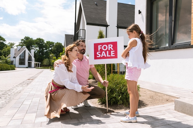 Pleasant nice parents looking at their daughter while asking what she doesnt like about the house