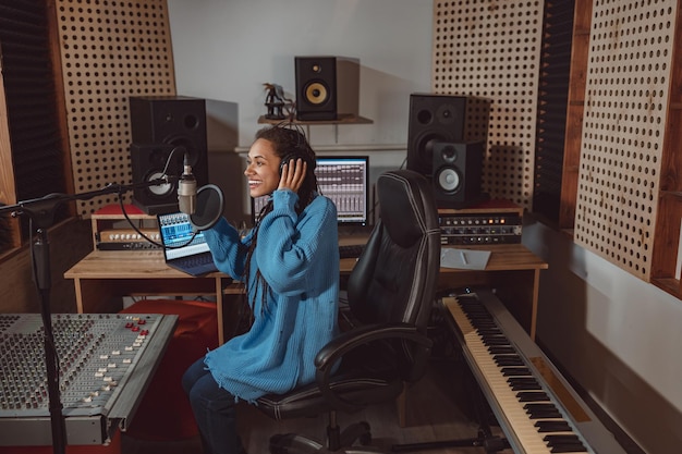 pleasant radio presenter wearing headphones talking into professional microphone in a broadcasting and recording studio