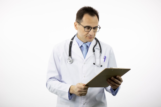 Pleasant senior age doctor looks on clipboard with diagnosis. Copy space