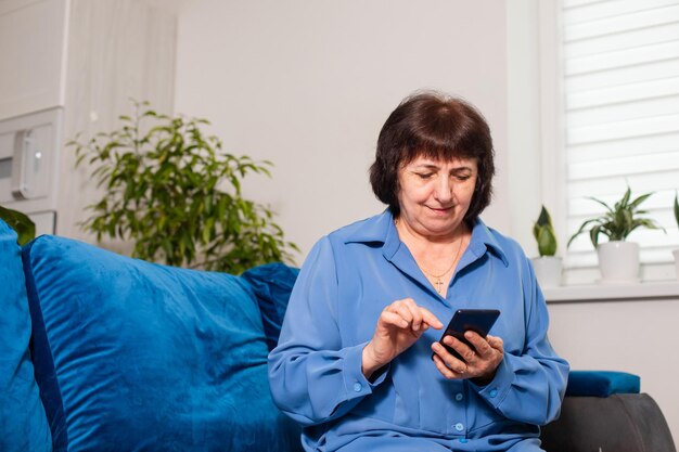 Pleasant senior aged woman browsing social media on smartphone