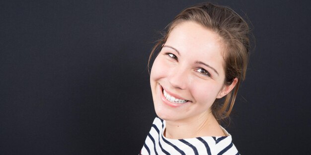 Pleasant and smiling face of a young pretty girl on a black background