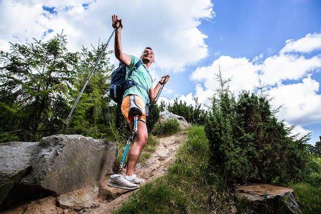 Pleasant smiling man with prosthesis trying Nordic walking while feeling happy