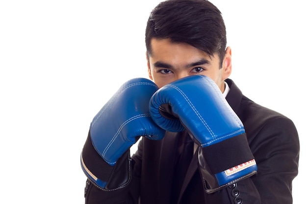 Pleasant young man with black hair in white shirt and black suit with tie and blue boxing gloves