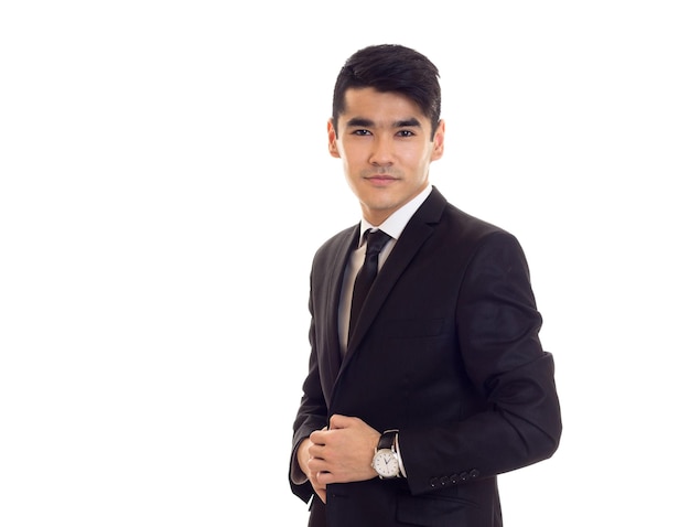 Pleasant young man with black hair in white shirt and  tuxedo with black tie and expensive watch