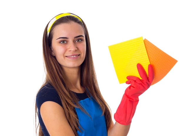 Pleasant young woman in blue Tshirt and apron with red gloves holding dusters in studio