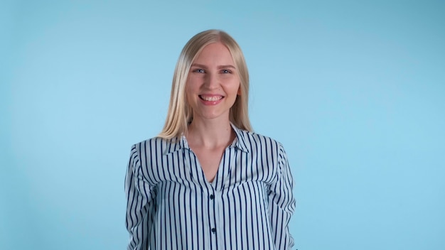 Photo pleasantlooking woman turning around and smiling to the camera blue background