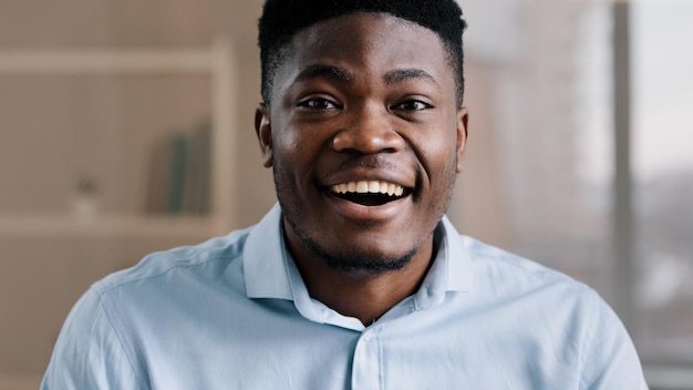 Pleasantly surprised african american man wears blue shirt makes big eyes feels shock open mouth in