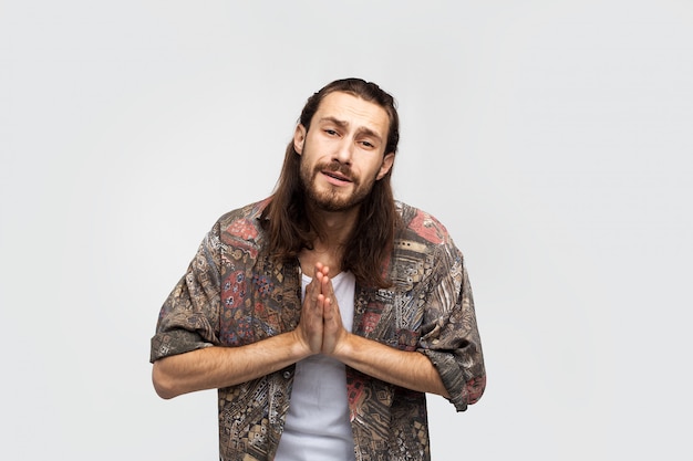 Please! Hand gesture prayer, asks for something higher powers, hope and gratitude. Hipster traveler stylish carefree man on a white studio background, people lifestyle