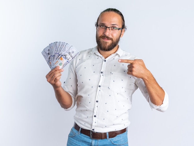 Pleased adult handsome man wearing glasses showing and pointing at money 