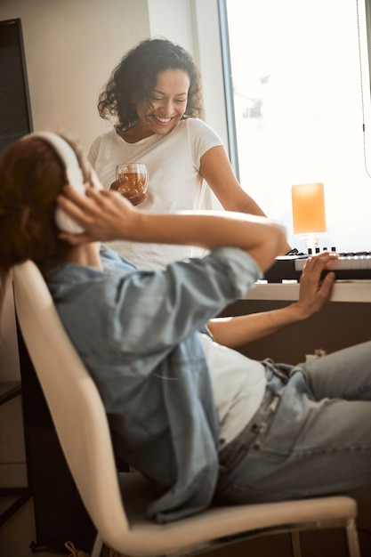 Pleased brunette keeping smile on her face while looking at synthesizer