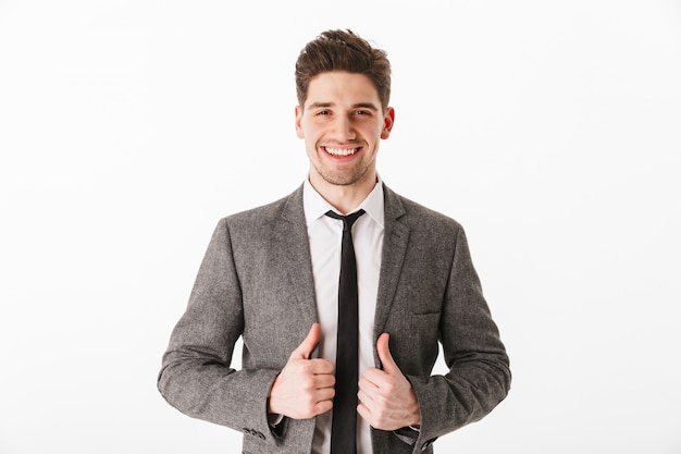 Pleased business man holding jacket  over white wall