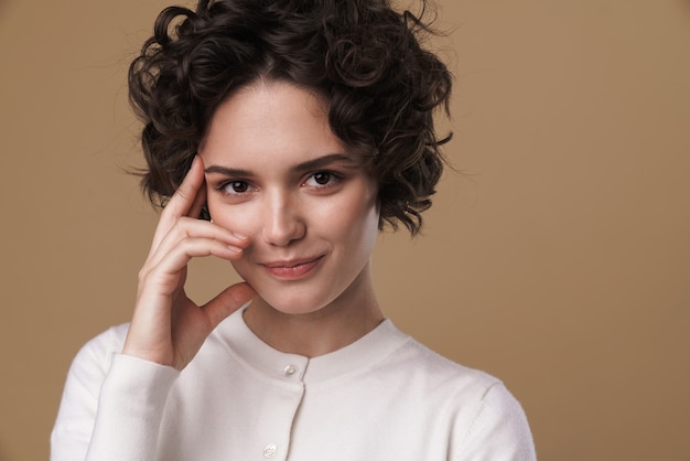 pleased caucasian woman posing and looking at front isolated over beige wall