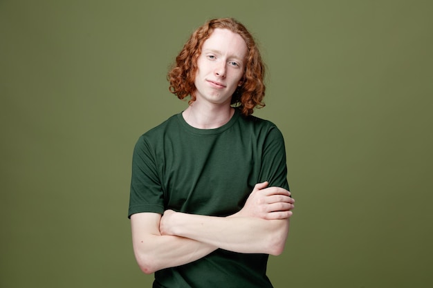 Pleased crossing hands young handsome guy wearing green t shirt isolated on green background