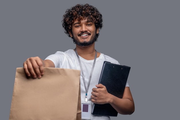 Pleased deliveryman posing for the camera against the gray background