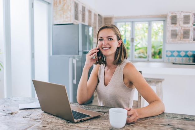 Pleased female talking on phone at home