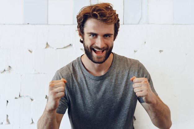 Pleased joyful bearded man against rough wall, portrait