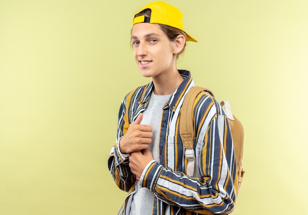 pleased looking front young guy student wearing backpack with cap isolated on olive green wall