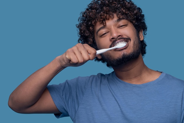 Maschio soddisfatto che usa uno spazzolino da denti durante la procedura di spazzolamento dei denti