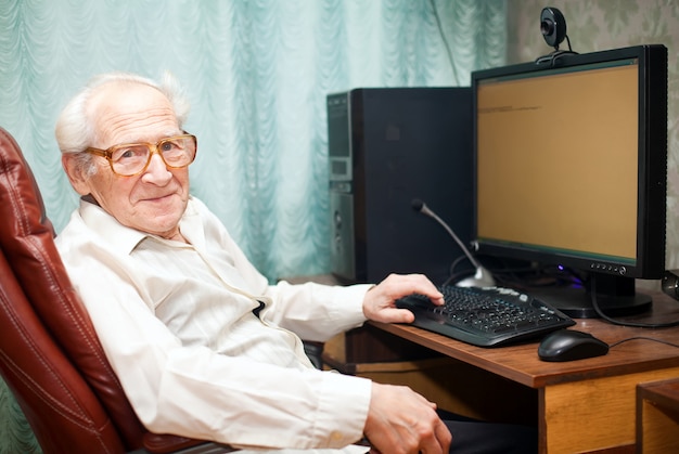 Photo pleased old man near computer