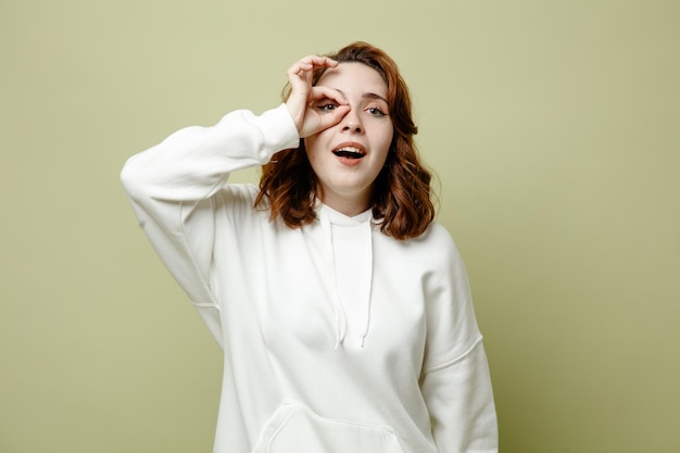 Pleased showing gesture young female wearing white sweater isolated on green background