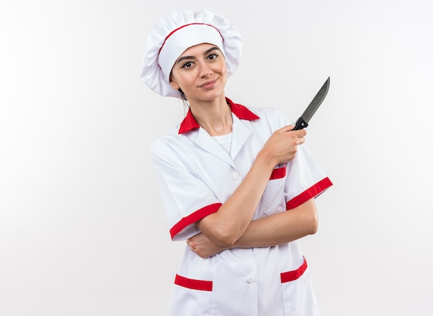 Pleased young beautiful girl in chef uniform holding knife 