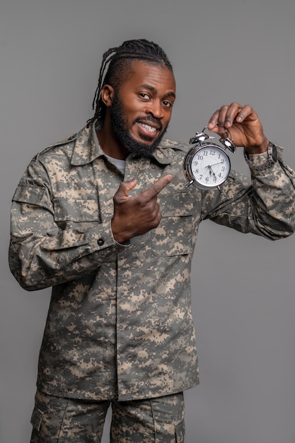 Pleased young military man showing time on his timepiece