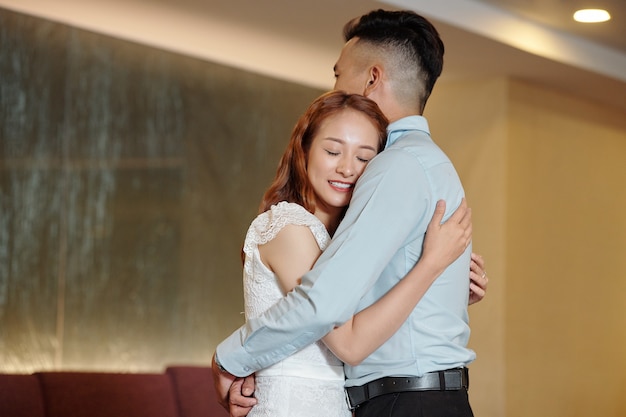 Pleased young woman giving warm hug to her boyfriend