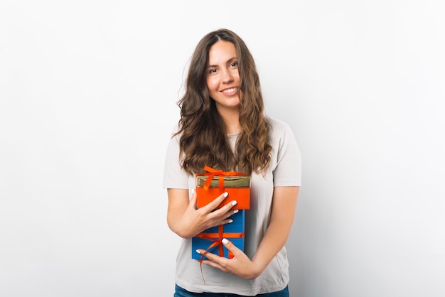 Lieta giovane donna è in possesso di alcune confezioni regalo su sfondo bianco.