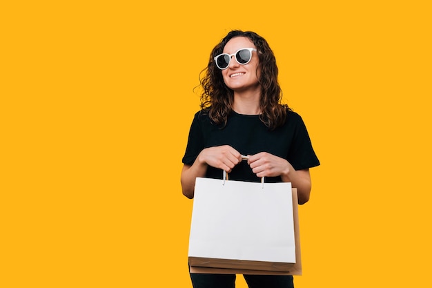 Pleased young woman is holding some paper shopping bags ready for mock up