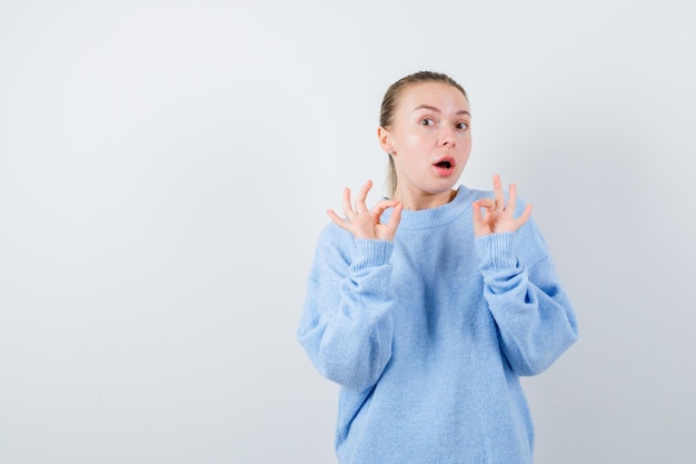 Pleasent girl is showing her emotion with her fingers on white background