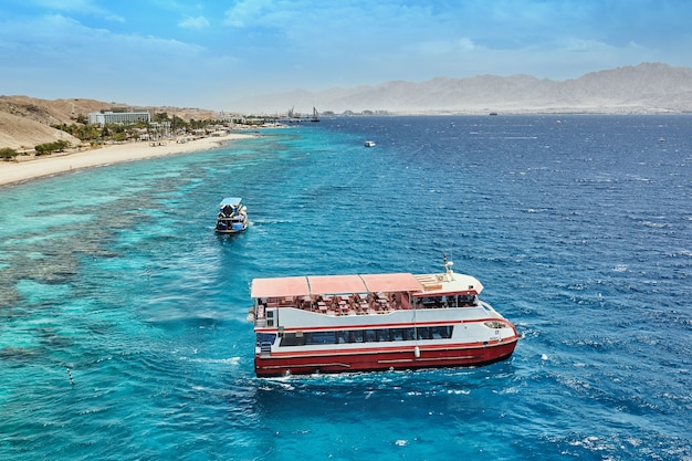 Pleasure boat for travel in the Red Sea, in Israel. Against the backdrop of the coastline and mountains.