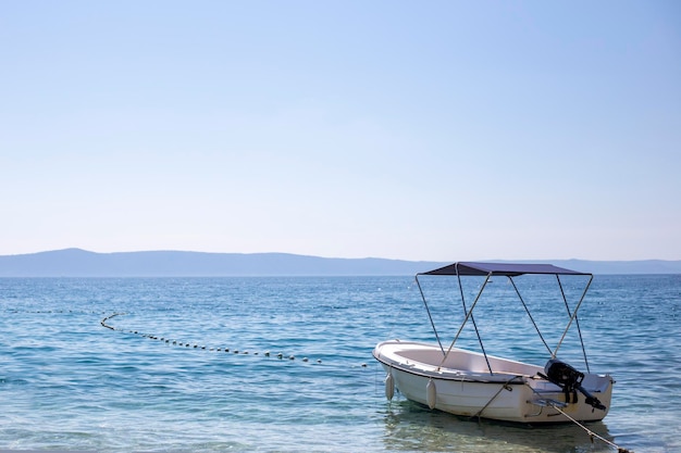 Pleasure boat with roof stands alone near the shore on the  seascape background