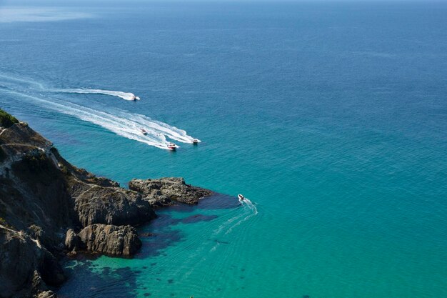 Pleasure boats approach the beautiful lagoon. View from the top of the cliff. Azure-emerald green sea water on a sunny day. High quality photo