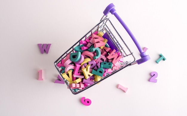 Plenty of wooden decorative letters in the small shopping trolley Knowledge buying concept