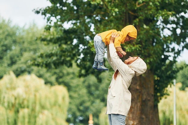 Plezier hebben moeder met haar zoon maakt een wandeling buiten in het park na de regen