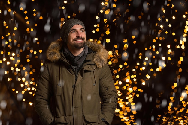 Plezier hebben op een kerstfee Jonge vrolijke man, warm gekleed, staat op de kerstmarkt