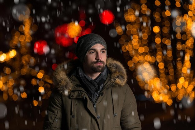 Plezier hebben op een kerstfee Jonge vrolijke man, warm gekleed, staat op de kerstmarkt