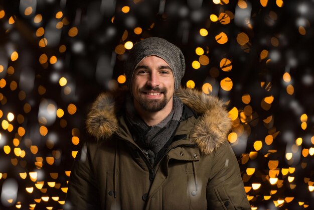 Plezier hebben op een kerstfee Jonge vrolijke man, warm gekleed, staat op de kerstmarkt