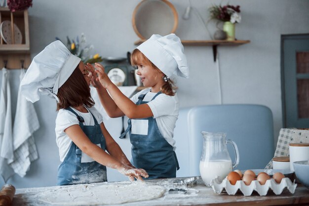 Plezier hebben tijdens het proces. Familie kinderen in witte chef-kok uniform bereiden van voedsel in de keuken.