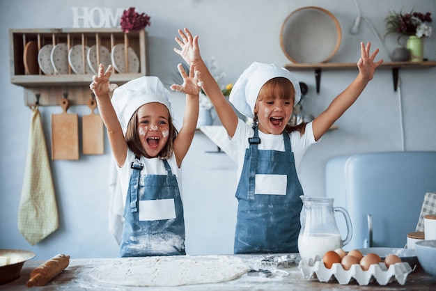 Foto plezier hebben tijdens het proces. familie kinderen in witte chef-kok uniform bereiden van voedsel in de keuken.