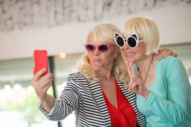 Plezier hebben. Twee senior opgewonden vrouwen die selfie maken en plezier hebben