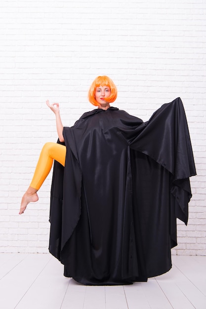 Plezier in beweging Voel je lichaam Dansende theaterartiest Dansen in mantel Meisje met lange benen in oranje panty dansen Vrouw gember pruik uitvoeren van moderne kunst dans Danser levensstijl